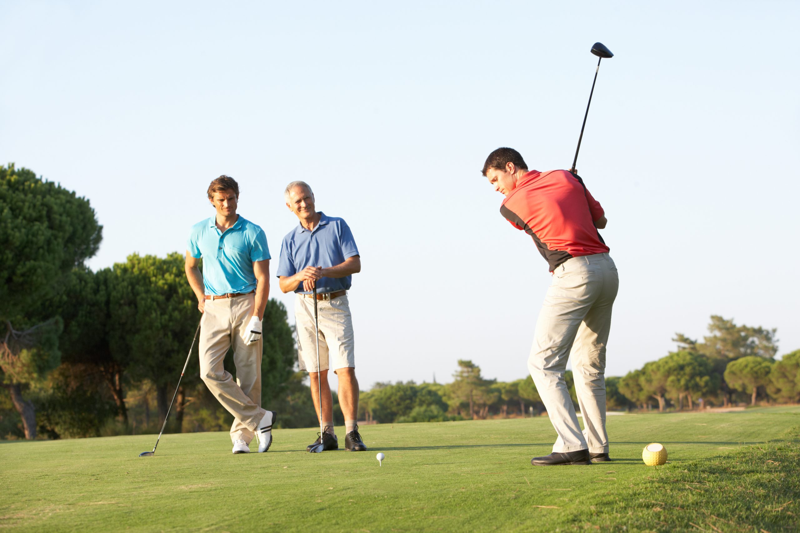 Group Of Male Golfers Teeing Off On Golf Course